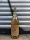 White wine bottle with minimalist kraft paper label  set against a metallic shutter with graffiti accents in an urban Berlin setting.