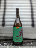 Bottle of Sauvignon Blanc Natür 42 natural wine with an turquoise artistic label, a litle orange demeter label on top, standing against a metallic background with silver and black accents.