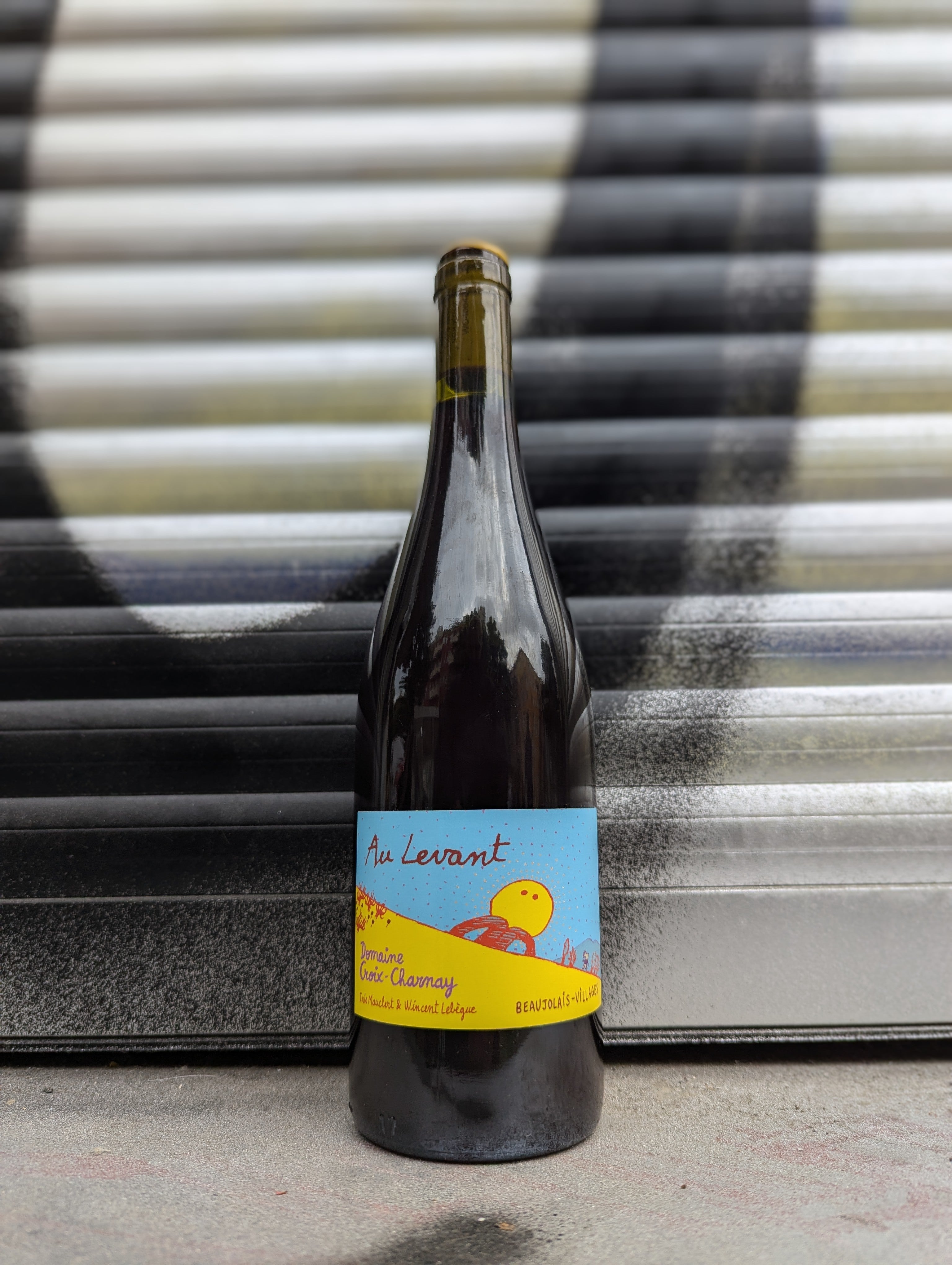 Red natural wine bottle set against a graffiti-covered shutter in an urban Berlin setting.